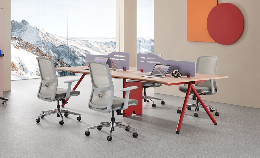 Un escritorio para cuatro personas con solapas y cuatro sillas de oficina de malla gris en la oficina.