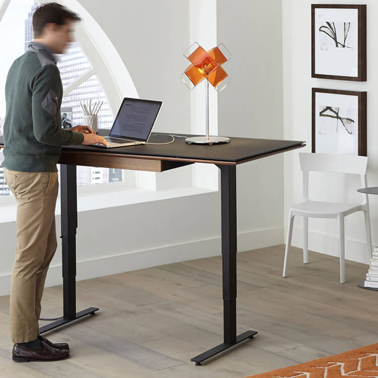 Hombre de pie sobre un escritorio de oficina ajustable para una configuración de trabajo ergonómica.
