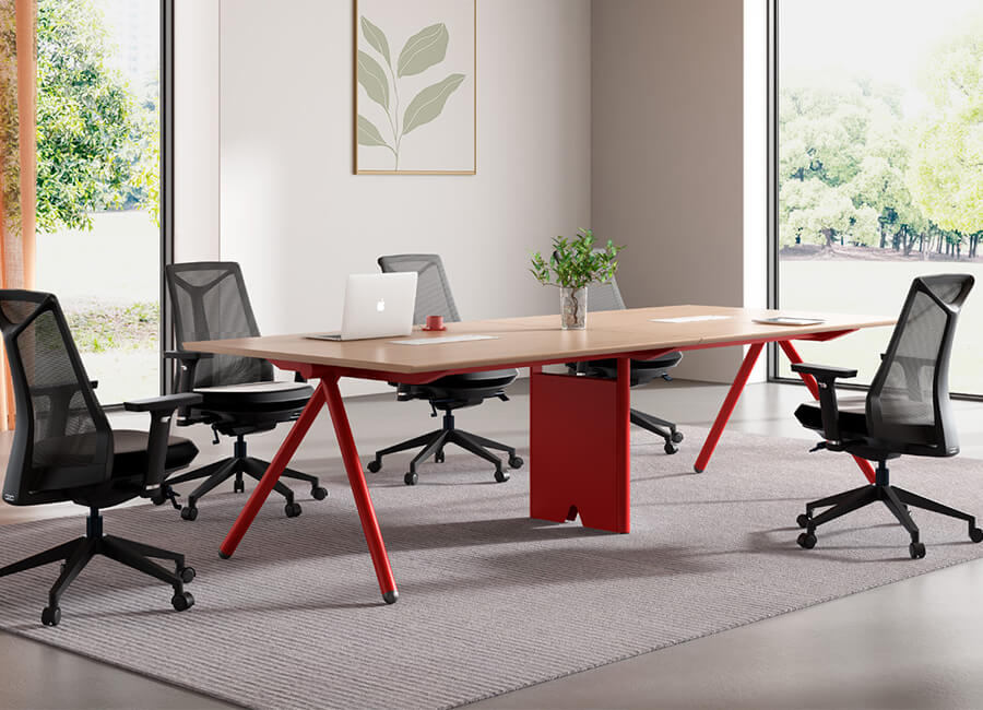 Una pequeña mesa de conferencias con una esquina roja y 4 sillas de malla de oficina negras con ruedas